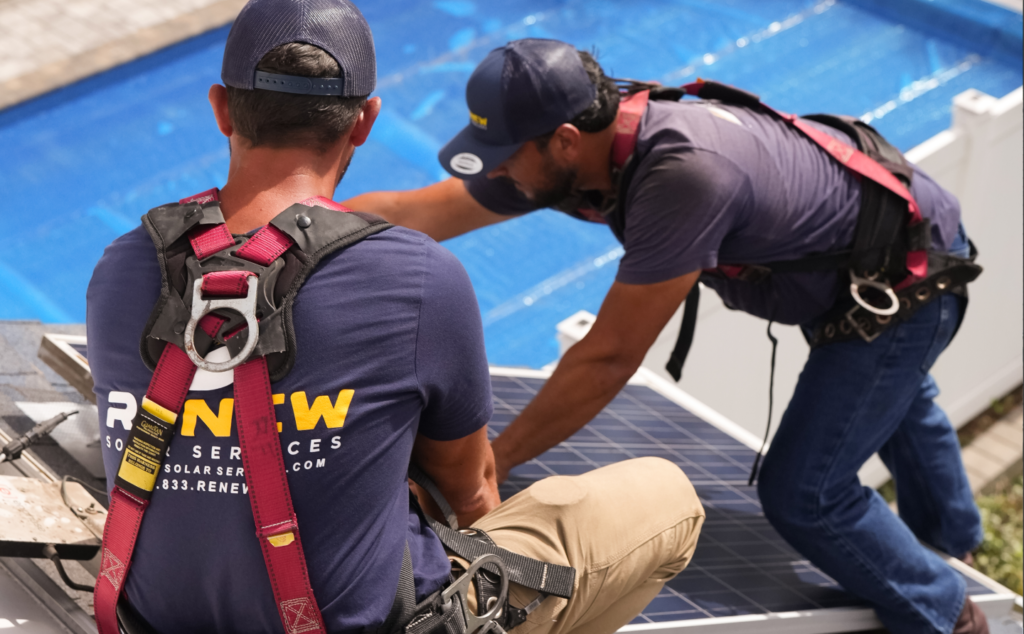 Two technicians working on a rooftop solar array