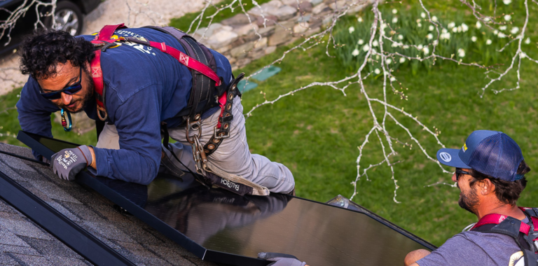 Technician in a safety harness working on a roof