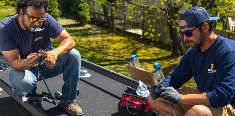 Two technicians working on solar wiring on a roof