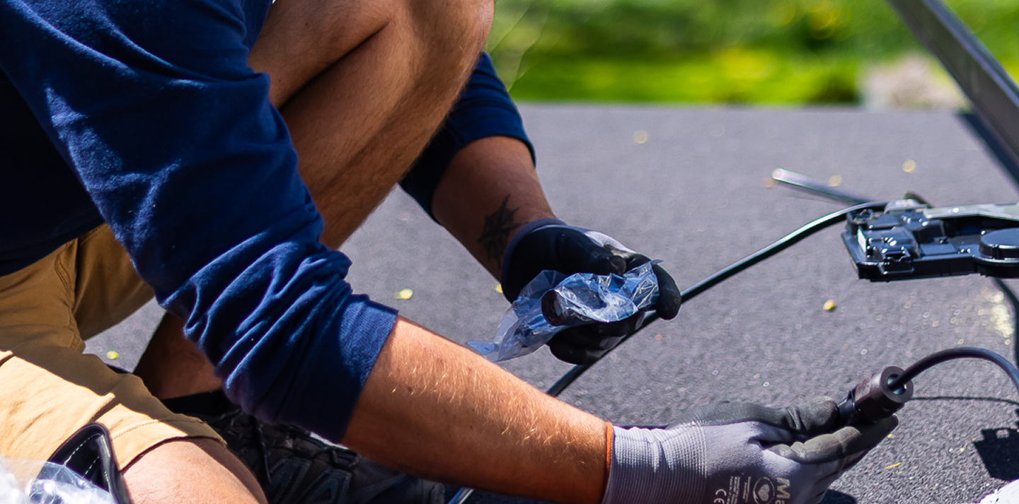 Technician connecting solar panel wiring connectors on a roof